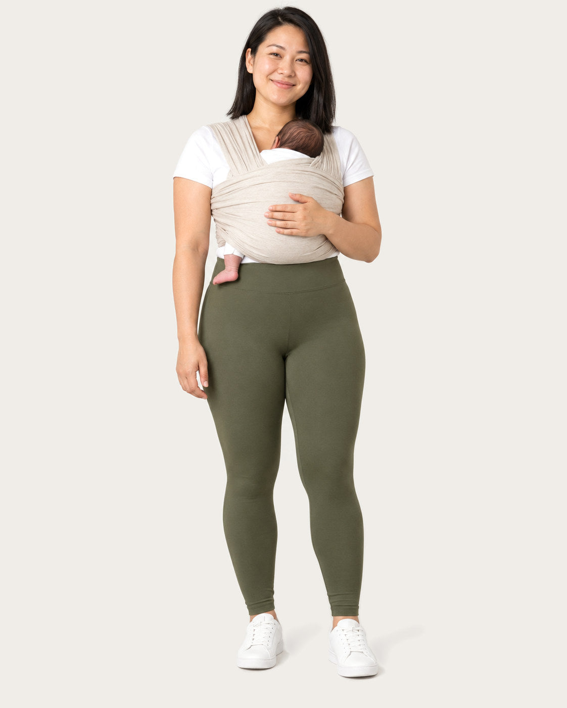 New mom in olive green postpartum leggings with her newborn in a soft wrap carrier