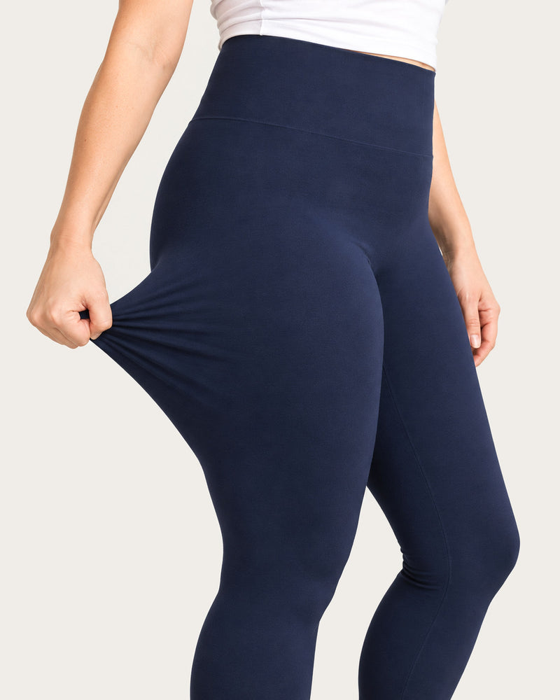 Hand pulling the knit of midnight blue leggings away from the thigh