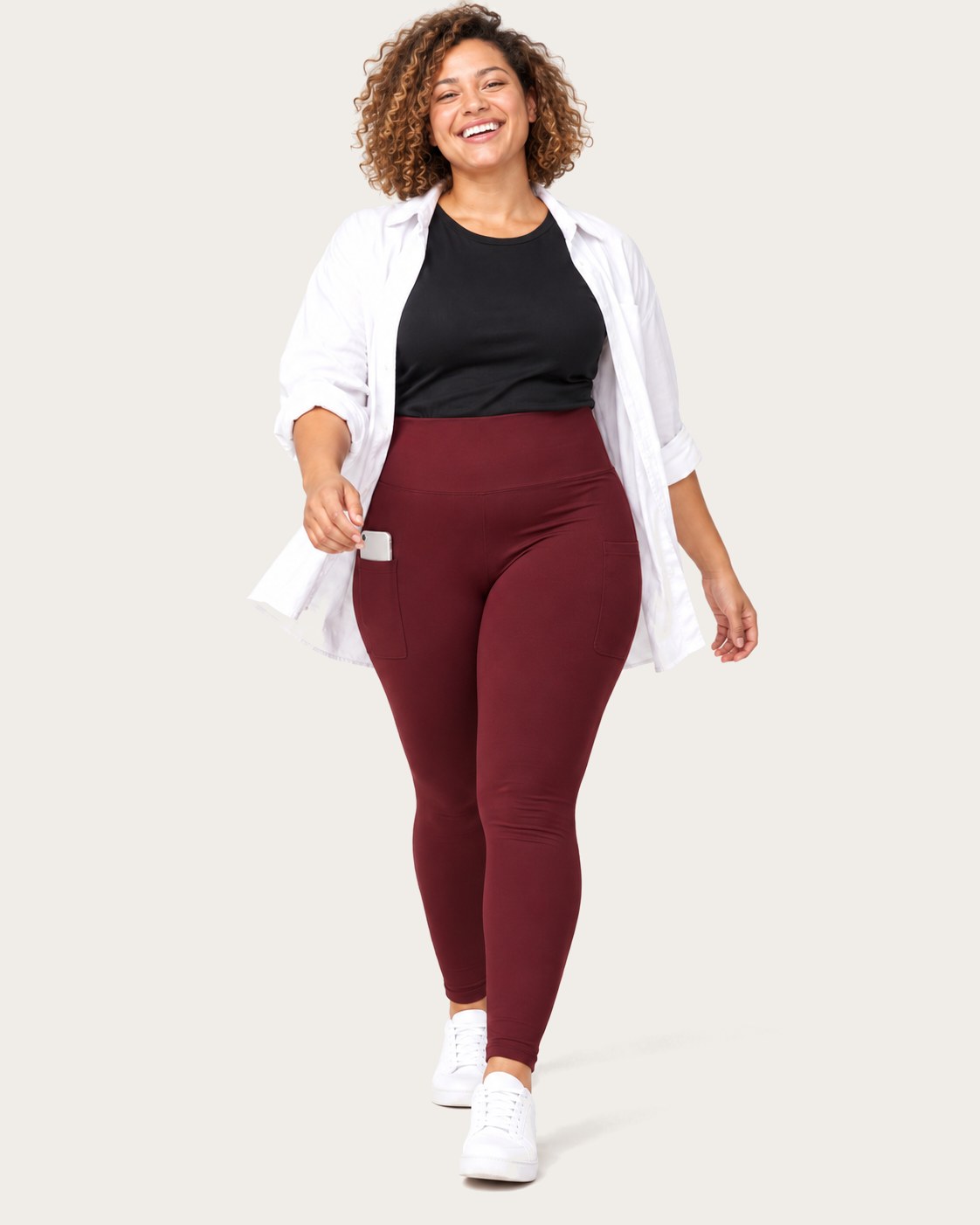 Laughing mom walking in burgundy leggings and an open white shirt, her phone in the side pocket