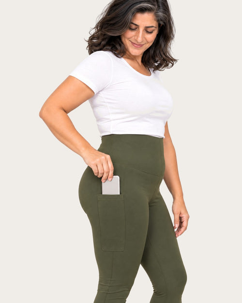 Mom sliding her phone into the side pocket of her olive green leggings