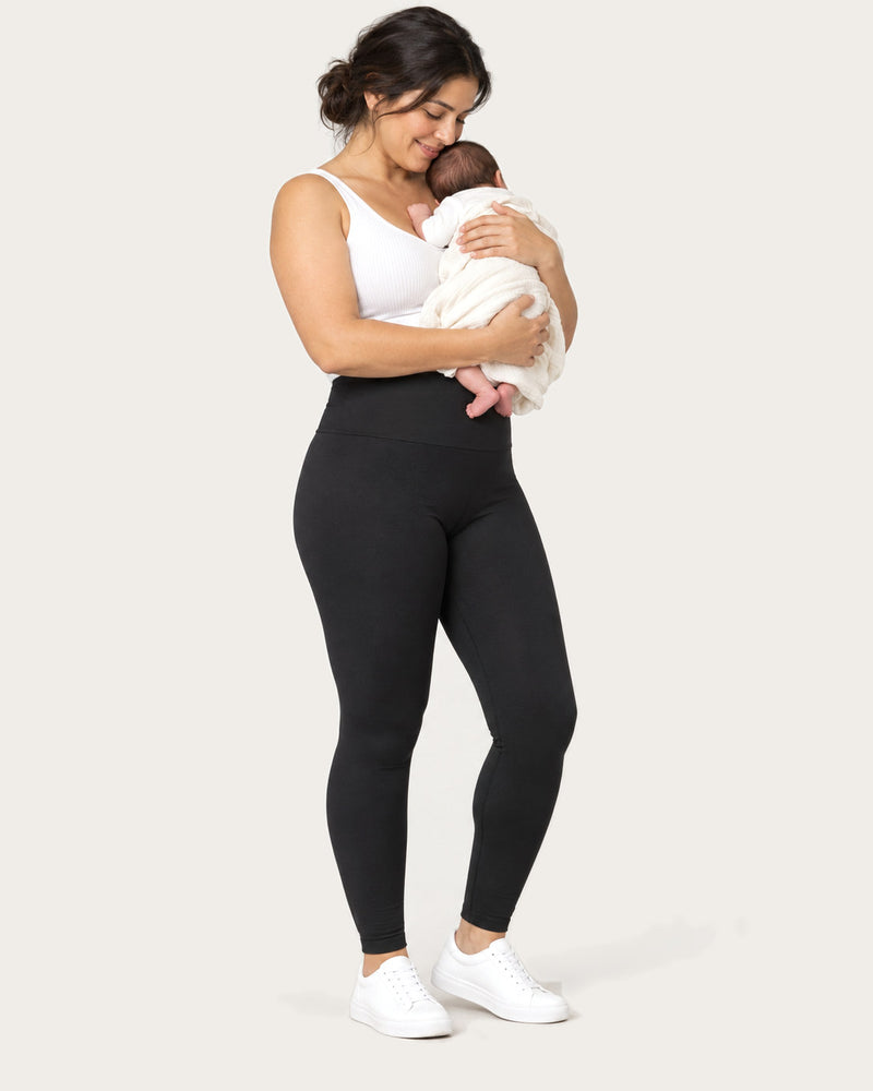 Mom in black leggings holding her swaddled newborn in her arms