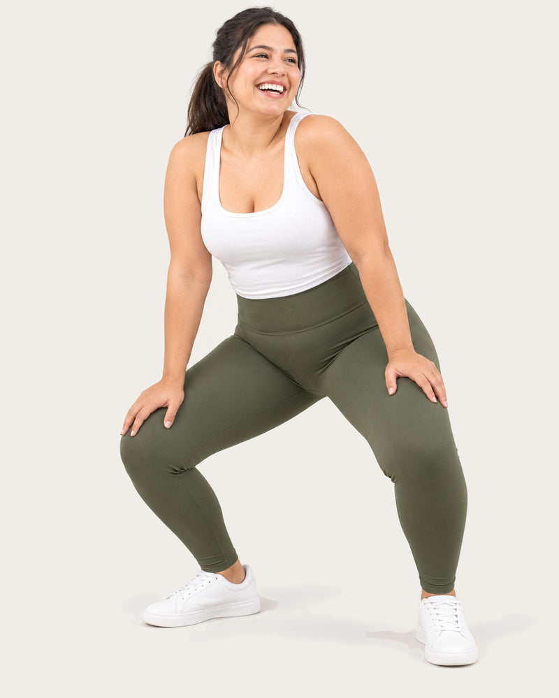 Laughing mom in a low squat wearing olive green leggings