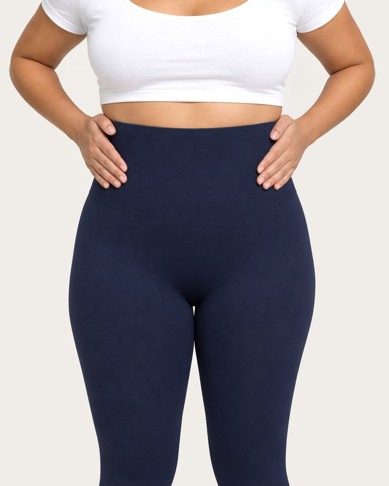 Hands smoothing the high waistband of midnight blue leggings