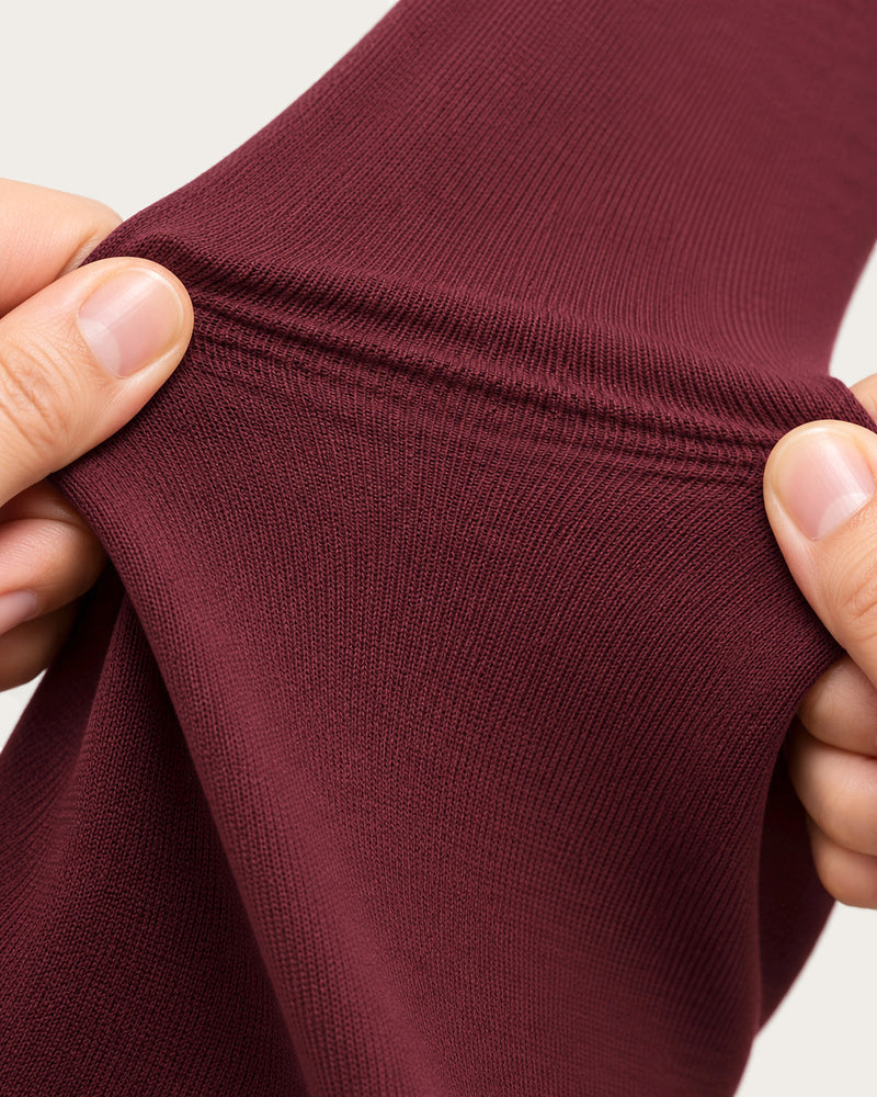 Close-up of the burgundy legging knit stretched between two hands