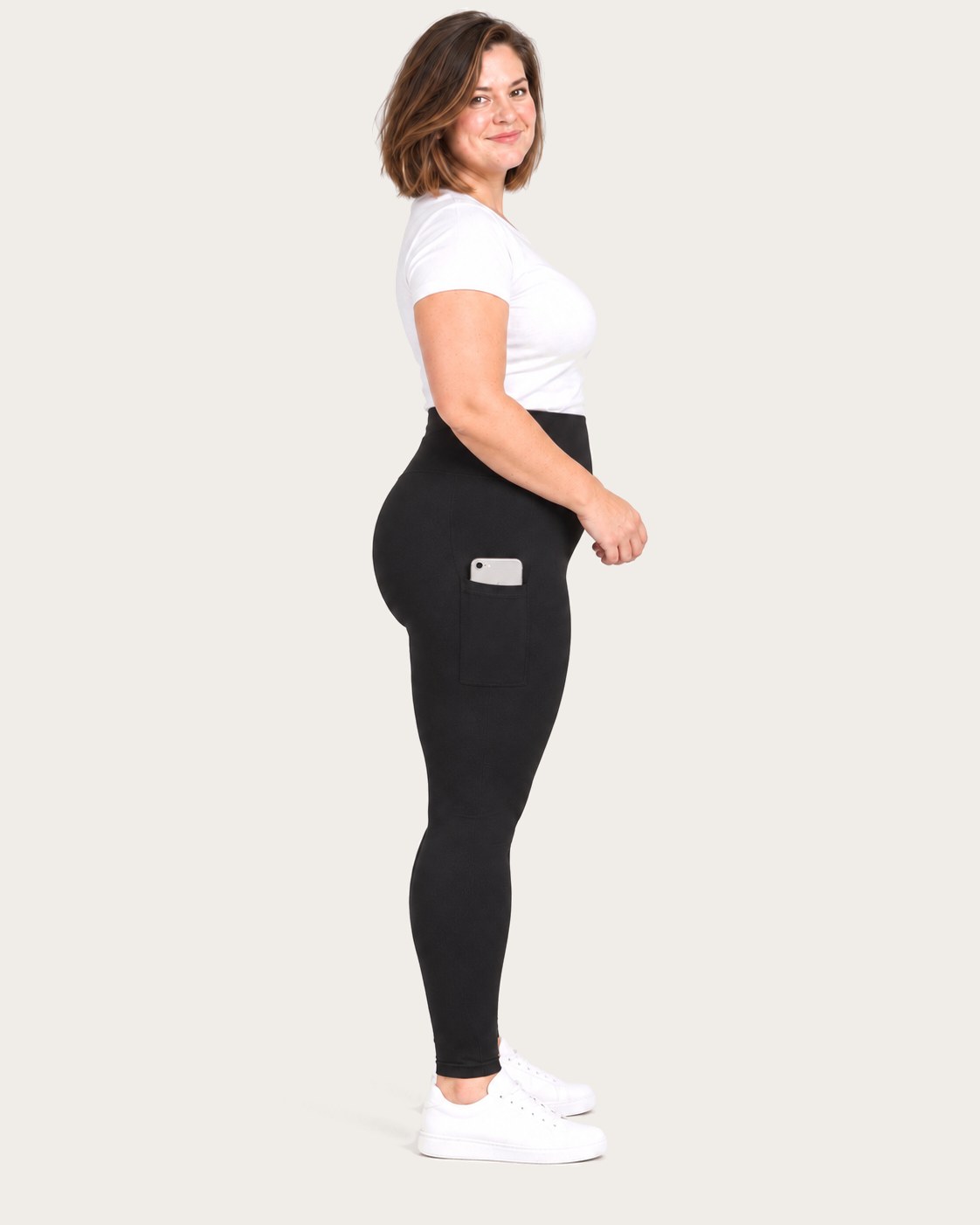 Side view of a mom in black postpartum leggings with her phone in the thigh pocket
