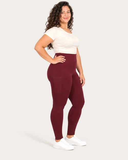 Mom in burgundy postpartum leggings with side pockets, three-quarter view