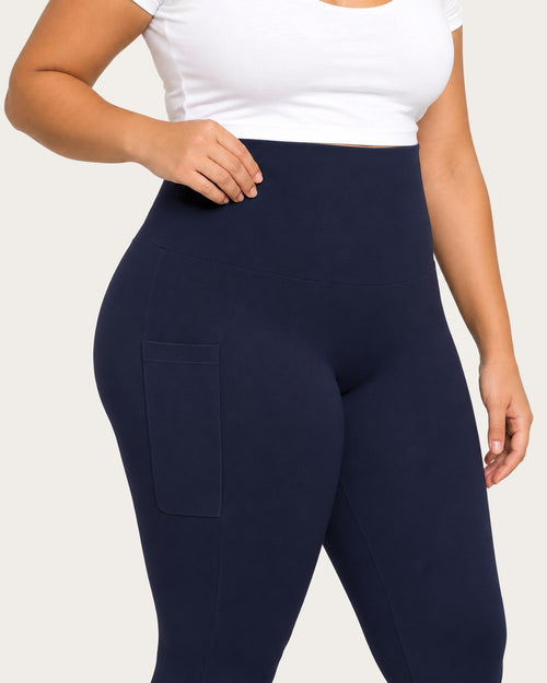Hand resting on the high waistband of midnight blue leggings